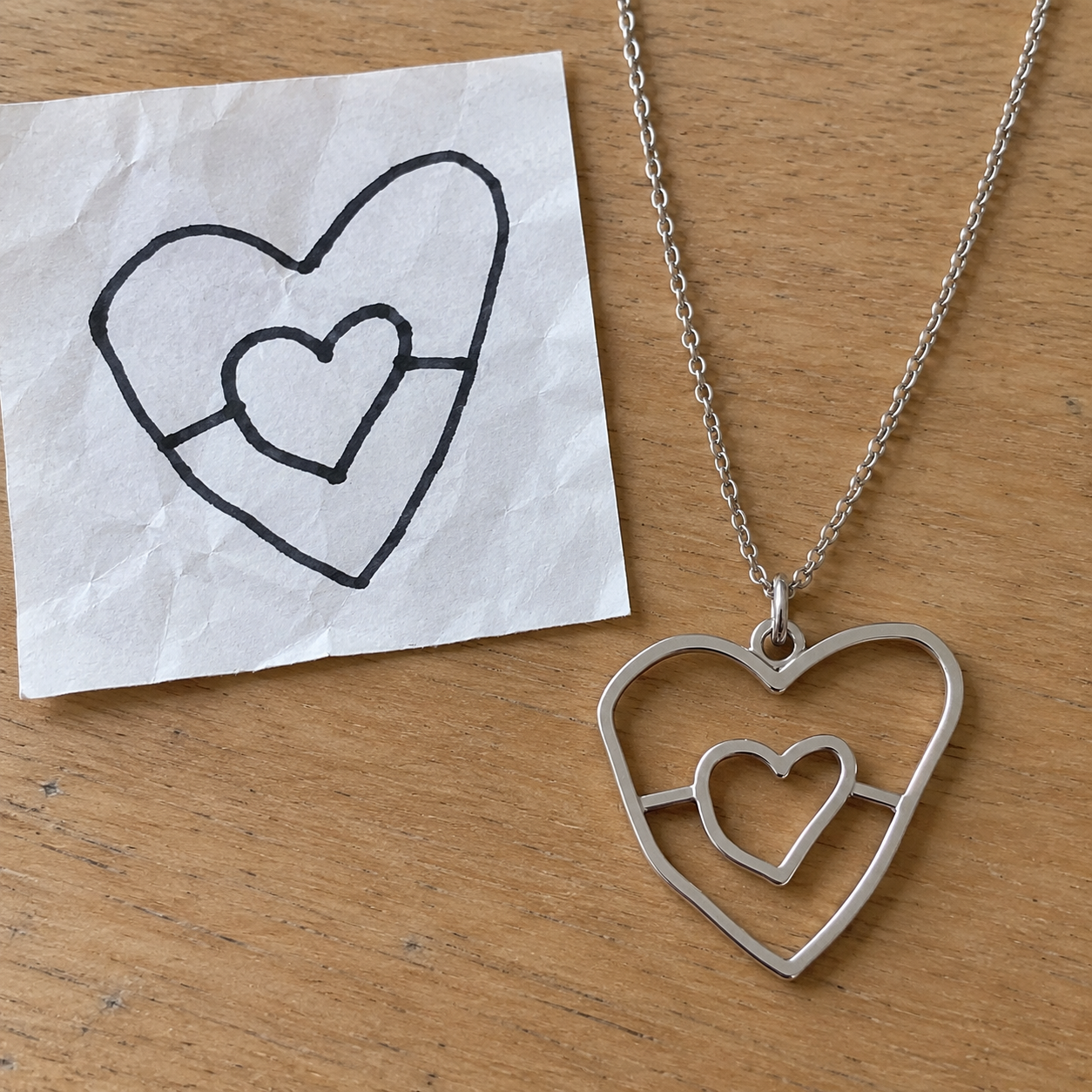 A child's heart drawing beside the matching Forever Line cut-out heart necklace